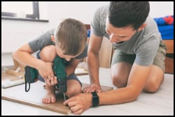 Father teaches son to use drill