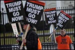 Protesters holding up Trump must go signs.